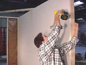Using screw gun to screw in drywall